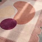 Close-up perspective of the Rose Veil rug highlighting the plush hand-tufted wool texture and the vibrant deep purple circle against the soft pink background.