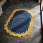 Perspective view of the Royal Indigo rug placed on a dark tiled floor, highlighting the rich blue tones and the elegant gold and teal border design.