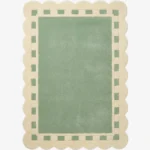 Top down view of the Sage Frame rug featuring a solid sage green center surrounded by a cream border with a decorative green square pattern and scalloped edges.