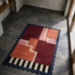 Perspective view of the Stepped Field rug placed on a dark tiled floor, showcasing the plush hand-tufted wool texture and the architectural "stepped" composition.