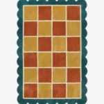 Top down view of the Sunbathe Quilt rug featuring a vibrant checkered pattern in rust orange, mustard yellow, and peach, framed by a cream line and a teal green scalloped border.