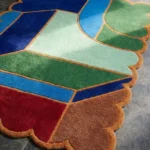 Close-up perspective of the Sunroom Courtyard rug, highlighting the plush hand-tufted wool texture and the abstract architectural pattern in contrasting colors like mint, teal, and burgundy.