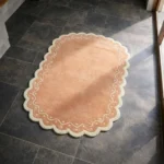 High angle perspective of the Terra Manor rug placed on a dark tiled floor, highlighting the soft hand-tufted wool texture and the vintage-inspired scalloped edge design.