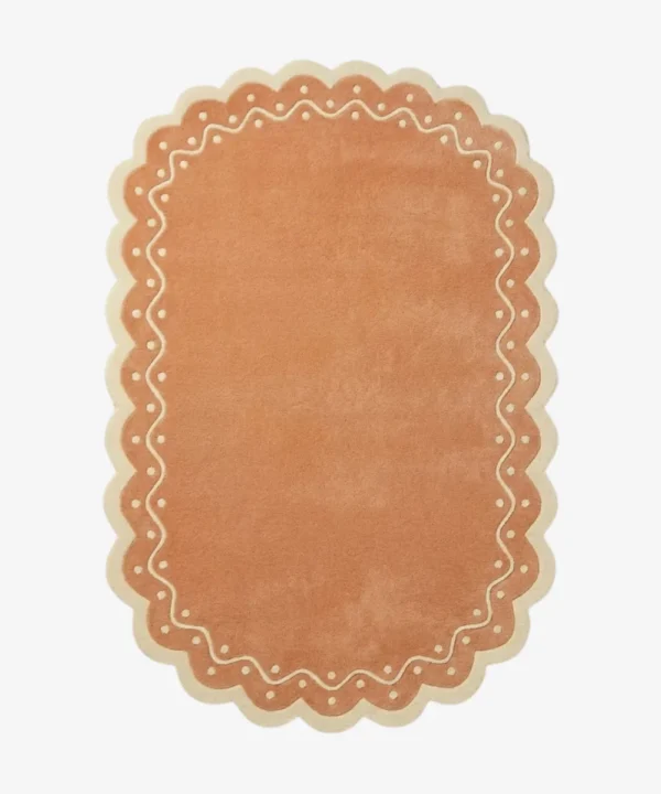Top down view of the Terra Manor rug featuring a warm rust terracotta background with a decorative cream border containing a wavy line and polka dots.