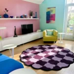 Perspective view of the circular Amora Weave wavy checkerboard rug styled in a bright, eclectic living room with pastel pink and teal walls, resting beautifully on a light hardwood floor.