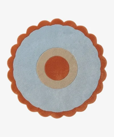 Top-down view of the Aurora Ring round rug, featuring a rust orange center circle, a cream middle ring, a wide light blue outer field, and a rust orange scalloped border.