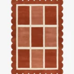 Top-down view of the rectangular Canyon Panel rug featuring a cream windowpane grid with nine alternating color-blocked squares in shades of rust and peach, framed by a thick terracotta scalloped border.
