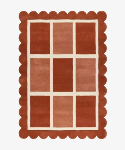 Top-down view of the rectangular Canyon Panel rug featuring a cream windowpane grid with nine alternating color-blocked squares in shades of rust and peach, framed by a thick terracotta scalloped border.