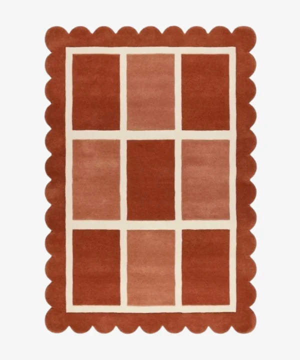 Top-down view of the rectangular Canyon Panel rug featuring a cream windowpane grid with nine alternating color-blocked squares in shades of rust and peach, framed by a thick terracotta scalloped border.