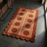 Perspective view of the Cocoa Ridge runner rug styled in a modern sunlit hallway, showcasing its warm earthy color palette and playful circle-in-square geometric design contrasting against a dark grey tile floor.