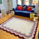 Perspective view of the Elvare Bloom scalloped rug styled in a bright, eclectic living room, beautifully contrasting with a dark blue sofa and resting on a light hardwood floor.