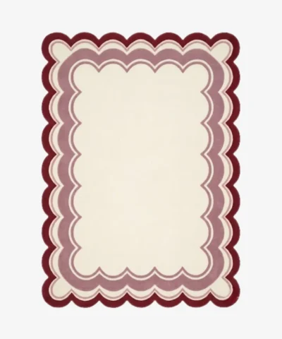 Top-down view of the rectangular Elvare Bloom rug, featuring a large cream center framed by concentric, scalloped border layers in soft pink, lavender, and a deep plum outer edge.