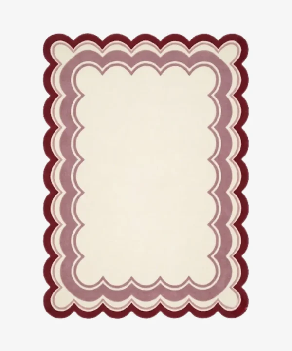 Top-down view of the rectangular Elvare Bloom rug, featuring a large cream center framed by concentric, scalloped border layers in soft pink, lavender, and a deep plum outer edge.