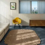 Perspective view of the Latte Halo scalloped rug styled in a modern, sunlit living space, complementing a bright yellow accent chair and resting beautifully on a contrasting dark floor.