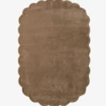 Top-down view of the rectangular Latte Halo rug, featuring a solid warm tan field and a continuous scalloped border accented by a delicate carved line detail.