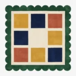Top-down view of the square Mosaic Verve rug, featuring a cream grid with alternating colorful squares in mustard yellow, navy blue, and rust orange, all bordered by a thick forest green scalloped edge.