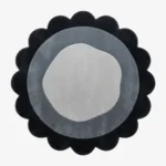 Top-down view of the circular Noctra Orb round rug, featuring a cream field with nested scalloped borders in soft black, gray, and a dark plum outer edge.