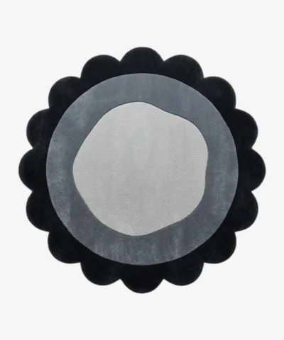 Top-down view of the circular Noctra Orb round rug, featuring a cream field with nested scalloped borders in soft black, gray, and a dark plum outer edge.