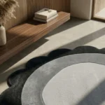 Close-up angled view of the Noctra Orb round rug in sunlight, showcasing the plush hand-tufted wool pile, the carved definition between the cream center