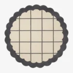 Top-down view of the circular Orbital Grid rug featuring a soft cream center with a classic dark grey windowpane grid, framed by a thick dark grey scalloped border.