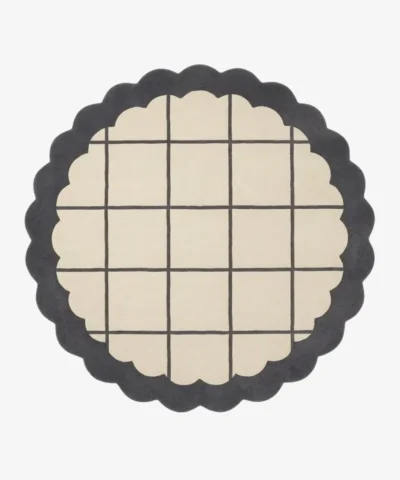 Top-down view of the circular Orbital Grid rug featuring a soft cream center with a classic dark grey windowpane grid, framed by a thick dark grey scalloped border.