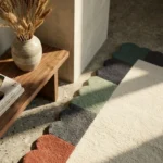 Close-up detail of the Palette Parade rug's hand-tufted wool texture, highlighting the dense, high-density pile of the terracotta and charcoal scalloped segments in the sunlight.