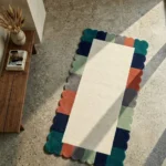 Perspective view of the Palette Parade runner rug styled on a polished concrete floor in a sunlit room, showcasing its vibrant architectural wavy border and clean minimalist design.