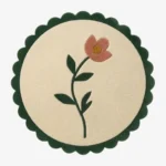 Top-down view of the circular Petal Poise rug, featuring a soft cream background adorned with a stylized pink flower and green stem, perfectly framed by a thick forest green scalloped border.