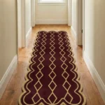 Long burgundy and gold Solyvr Axis Runner Rug with scalloped borders placed on a light hardwood floor in a well-lit home hallway.