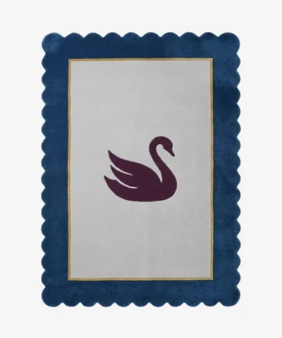 Top-down view of the Swan Crest hand-tufted wool rug featuring a central dark purple swan silhouette on a light grey rectangular field, framed by a thin gold line and a bold navy blue scalloped border.