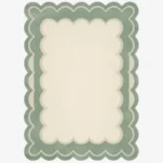 Top-down view of the rectangular Sylvena Crest rug, featuring a large solid cream center framed by a delicate inner wavy contour line and a thick, soft sage green scalloped outer border.
