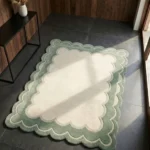 Perspective view of the Sylvena Crest scalloped rug styled in a modern, sunlit space with elegant wood paneled walls, resting beautifully on a dark slate floor next to a minimalist black console table.