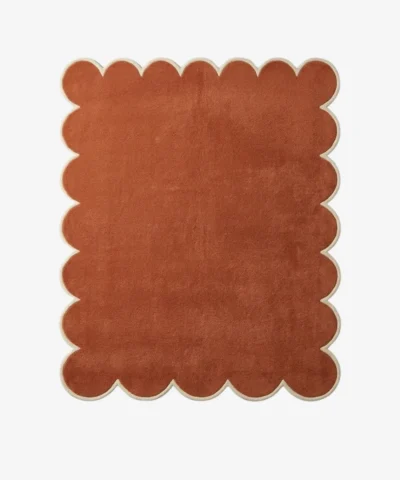 Overhead view of the hand-tufted Terryn Vale Wool Rug displaying a solid rust orange center with dense cut pile and a contrasting cream scalloped border.