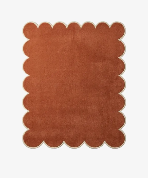 Overhead view of the hand-tufted Terryn Vale Wool Rug displaying a solid rust orange center with dense cut pile and a contrasting cream scalloped border.