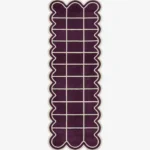 Top-down view of the Velquor Vane runner rug, featuring a rich plum purple background with a crisp cream geometric grid pattern, framed by a deeply contoured wavy cream border.