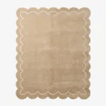 Top-down view of the rectangular Velune Nest rug, featuring a solid warm tan background bordered by a scalloped edge and a delicate, continuous cream inner line mimicking the wavy silhouette.
