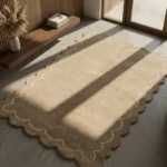 Perspective view of the Velune Nest scalloped rug styled in a serene, sunlit entryway with concrete floors, warm wood paneling, and minimalist decor.