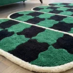 Close-up, low-angle view of the Verdure Drift rug, highlighting the dense, high-quality hand-tufted wool cut pile, the organic melted lines of the black and green checkers, and the plush cream segmented borders.