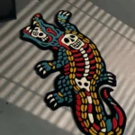 Close-up macro detail of the Alligator Skeleton rug, highlighting the dense hand-tufted wool pile and the crisp 3D carving of the skull, eye sockets, and sharp white teeth.