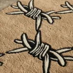 Extreme close-up detail of the Barbed Wire rug, emphasizing the thick hand-tufted wool texture and the deep 3D carving of the interconnected black and white barbed wire knots.