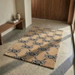 Wide perspective view of the Barbed Wire rug placed on a smooth concrete floor in a bright, minimalist hallway, positioned next to a sleek mid-century wooden bench.