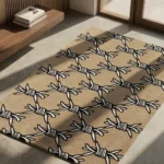 Perspective view of the rectangular Barbed Wire rug styled on a light concrete floor in a modern, sunlit entryway, featuring a repeating traditional tattoo black and white barbed wire pattern on a solid tan background.