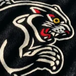 Angled perspective view of the Black Panther Tattoo Rug styled on a grey concrete floor in a bright modern room, next to a textured white pouf and a mid-century wooden cabinet bathed in natural sunlight and shadows.