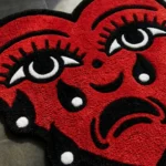 Close-up macro detail of the Crying Heart rug, highlighting the totally dense hand-tufted wool pile and the deep 3D carving of the eye and bright blue tear.