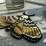 A detailed close-up shot of the lower section of the Death Head Moth rug, highlighting the carved textures of the gold, black, and cream wing patterns and the abdomen.