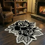 Wide perspective view of the Dual Rose black and white rug styled on a dark hardwood floor in a warm den, featuring a lit stone fireplace, a wooden bookcase, and a classic brown leather wingback chair.