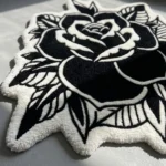 Angled close-up of the Dual Rose rug in sunlight, showcasing the plush hand-tufted black wool and the crisp white 3D carved lines that clearly define the overlapping flower petals.