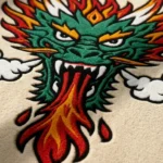 Close-up macro detail of the Firebreath Dragon Head rug, highlighting the dense hand-tufted 100% New Zealand wool pile, the crisp 3D carving of the green dragon scales, fierce white teeth, and the bright red fire and smoke.