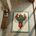 Wide perspective view of the Firebreath Dragon Head rug placed on a smooth concrete floor in a bright, minimalist room, showcasing its bold traditional tattoo flash design and structured zig-zag border.