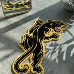 Close-up macro detail of the Neo-Traditional Panther rug, highlighting the dense hand-tufted New Zealand wool pile and the precise 3D carving of the panther's face, sharp teeth, red tongue, and yellow eye.